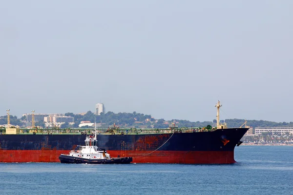 Cargo ship arriving at port, assisted by tugboat — Stock Photo, Image