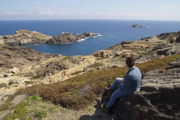 Mujer sentada en una roca, junto al mar — Foto de Stock