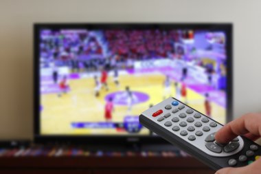 Remote control in the hand, during a basket match clipart