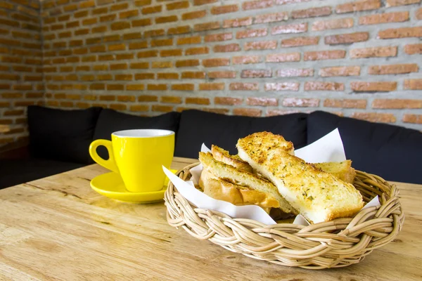 Roti bawang putih disajikan dalam keranjang dengan secangkir kopi di atas meja — Stok Foto