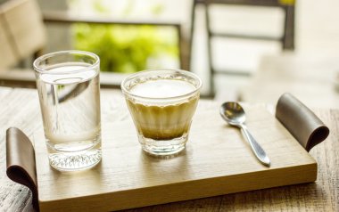 Fincan cappuccino kahve kahve masada ahşap tepsi üzerinde hizmet veren su ile