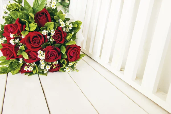 Кучка красных роз на белой деревянной скамейке — стоковое фото