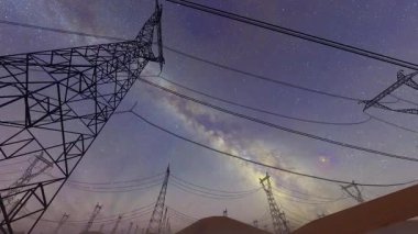 Geceleri yıldızlı gökyüzünün altında yüksek voltajlı elektrik hattı kulesi