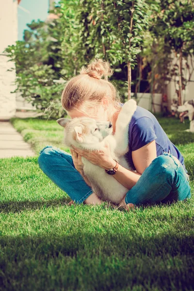 Young girl playing with a dog. Puppy Siberian Husky.Beautiful woman with husky outdoors.Woman with smiling siberian husky dog, sitting on a sunny day, on a walk with dog. — Stock Photo, Image