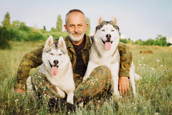 Yaşlı adam bir haystack onların köpekleri ile oturan sakallı yaz günbatımı zevk. Siberian dış yapraklar kırsal kesimde.