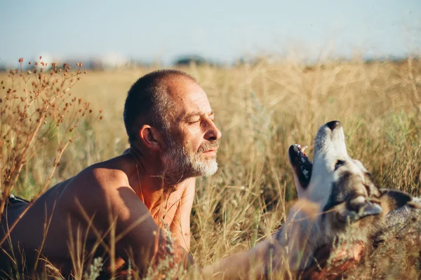 Öreg ember játszik a kutyájával, Szibériai Husky. — Stock Fotó