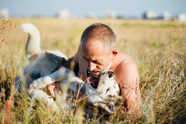Velho brinca com seu cão Husky siberiano. Estilo de vida. Recreação ativa . — Fotografia de Stock