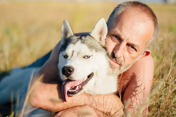 늙은 남자가 그의 강아지 시베리안 허스키와 함께 재생합니다. 생활양식입니다. 레저. — 스톡 사진