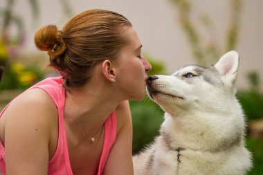 İki köpek ile oynayan genç kız. Köpek yavrusu Sibirya Husky.