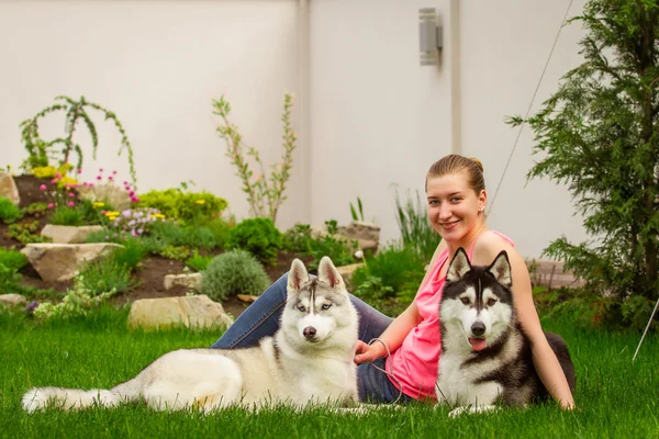 Молодая девушка играет с двумя собаками. Щенок Сибирский Хаски . — стоковое фото