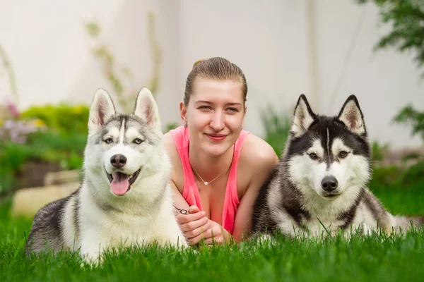 Jovencita jugando con dos perros. Cachorro siberiano Husky . —  Fotos de Stock