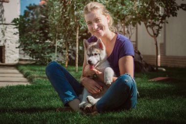 Genç kız bir köpekle oynamayı. Köpek yavrusu Sibirya Husky.