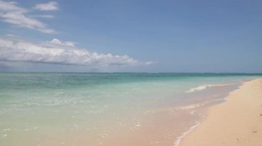 Sakin, el değmemiş bir kıyı şeridi. Kıyıda hafif dalgalar çakıyor. Soluk yeşilden koyu maviye büyüleyici okyanus renklerini sergiliyor. Yüksek kalite 4k görüntü