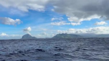 Kabarık beyaz bulutlar altında uzak tropikal adaların bulunduğu açık okyanus manzarası, uzak noktalardaki doğanın dokunulmamış güzelliğini, dinginliğini ve macera duygusunu çağrıştırıyor.. 