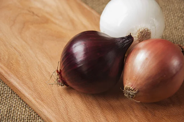 Verschillende uien op een bord op een achtergrond plundering, jute — Stockfoto