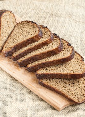 Çuval bezi arka plan üzerinde ahşap kesme tahtası üzerinde taze ekmek dilimi