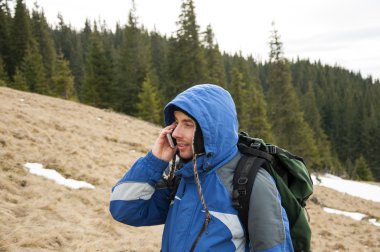 Kış dağlarda smartphone cep telefonu ile konuşurken uzun yürüyüşe çıkan kimse 