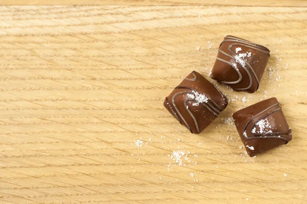 海塩とチョコレートトリュフキャンディー 木の質感の背景に積層塩チョコレート 一つのトリュフを中心に選択的にフィールドの浅い深さ — ストック写真