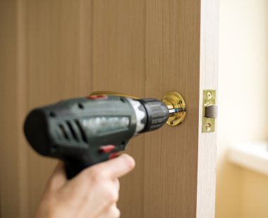 Bir tornavida kullanarak kapı kilit montajı. Ahşap kapı içine elektrikli matkap ile kilit yüklemeyi marangoz