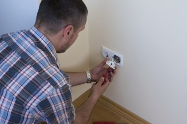 Yeni geçerli yuva tornavida ile yükleme elektrikçi. Elektrik prizine veya soket - closeup elektrikçi eller üzerinde yükleme