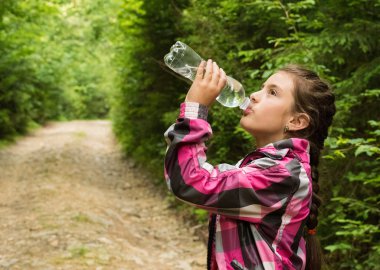 Güzel kız ormanda bir yürüyüş sırasında su içer. Kız içme suyu açık portresi.