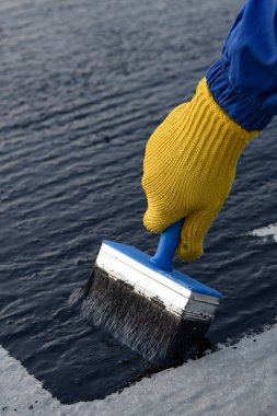 İşçi temel üzerine bitumen mastic uygular