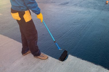 Worker applies bitumen mastic on the foundation clipart