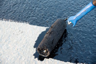 İşçi temel üzerine bitumen mastic uygular