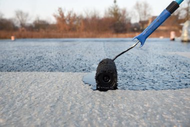 İşçi temel üzerine bitumen mastic uygular