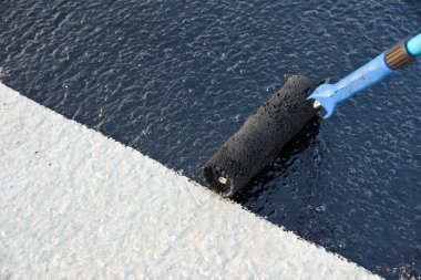 İşçi temel üzerine bitumen mastic uygular