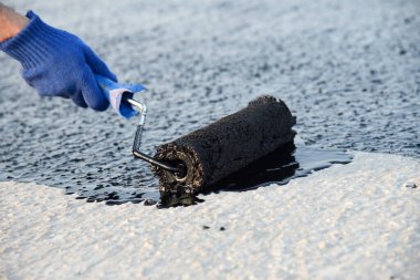 Worker applies bitumen mastic on the foundation clipart