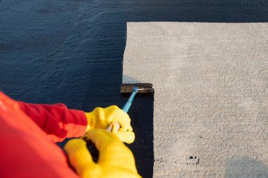 İşçi temel üzerine bitumen mastic uygular