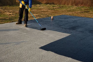 İşçi temel üzerine bitumen mastic uygular