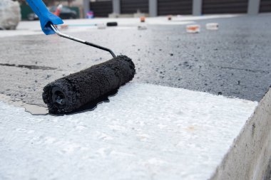 İşçi temel üzerine bitumen mastic uygular