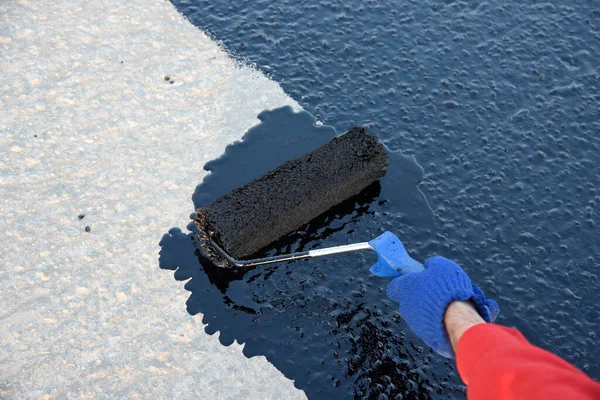 İşçi temel üzerine bitumen mastic uygular