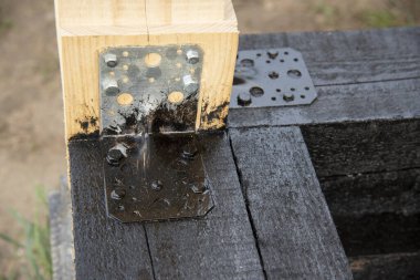 Terasın ahşap çerçevesine bituminöz astar takıyorum. Ahşap parmaklıklar ve tahtalar su geçirmez. Su geçirmez tahta. Bağlamak için metal köşe.