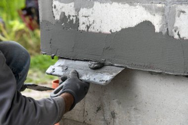 Fiberglas köşe takviye ağı inşaatlar için. İnşaat işçisi inşaat sırasında fiberglas köşe takviye ağını tamir ediyor..