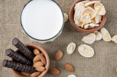 Bir bardak süt ile badem fındık, Mısır gevreği, çikolata, bir arka plan Sivas'tan, çuval bezi üzerinde,