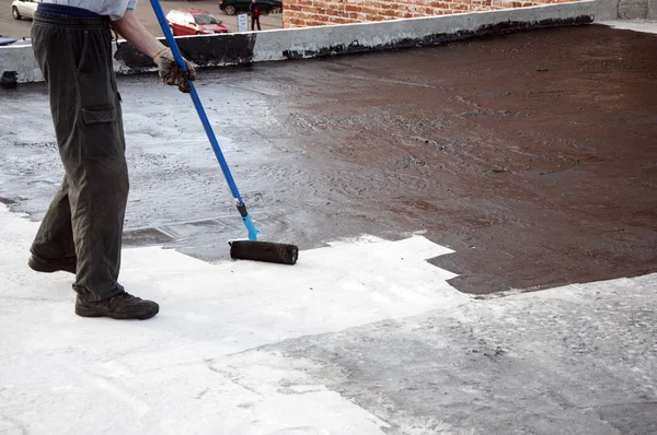 Roofer trabajador pintura betún praimer en superficie de hormigón por t —  Fotos de Stock