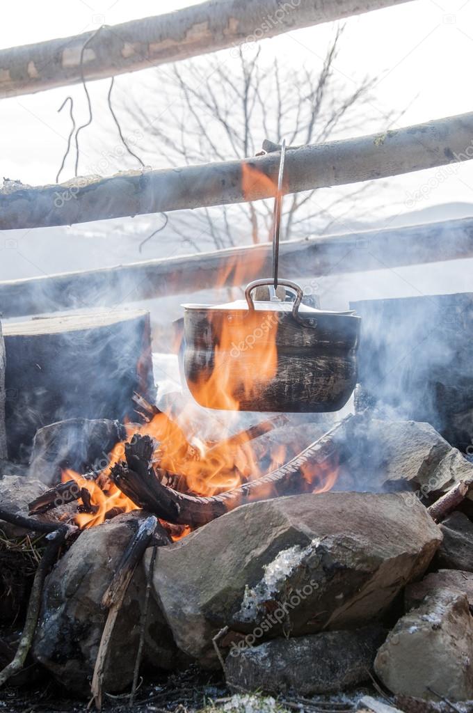 Cooking in field conditions, boiling pot at the campfire on picnic