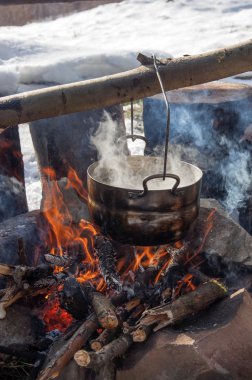 Saha koşullarında yemek pişirmek, piknikte kamp ateşinde demlik pişirmek.