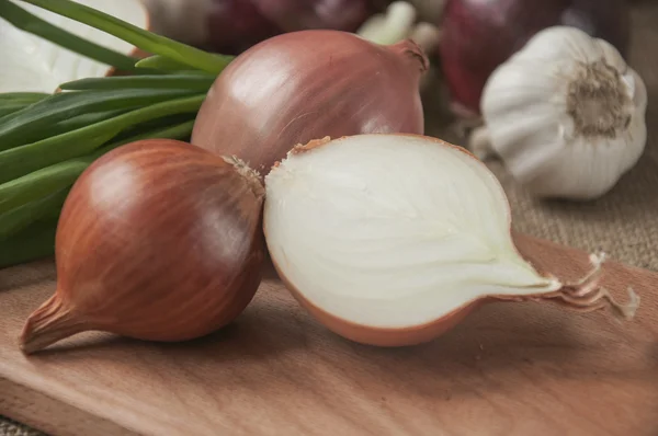 Various onions on a board on a background sacking, burlap — Stock Photo, Image