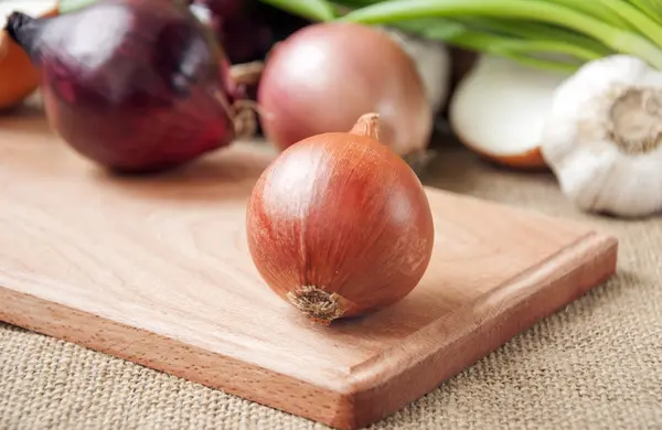 Verschillende uien op een bord op een achtergrond plundering, jute — Stockfoto