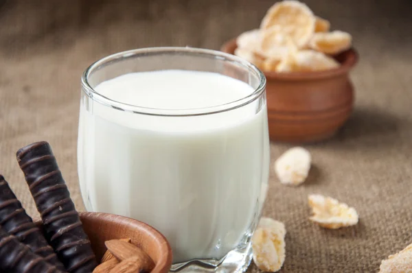 Ein Glas Milch mit Mandelnüssen, Cornflakes, Pralinen, auf Kleckerhintergründen — Stockfoto