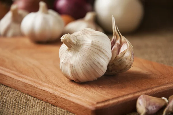 Knoflook op cutting board, close-up op plundering. jute-achtergrond — Stockfoto