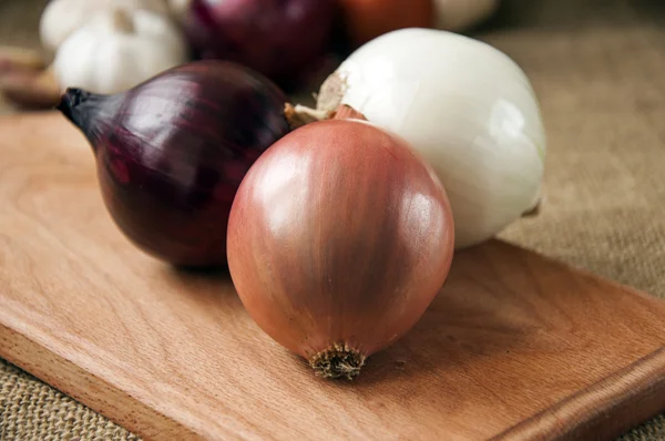 Verschillende uien op een bord op een achtergrond plundering, jute — Stockfoto