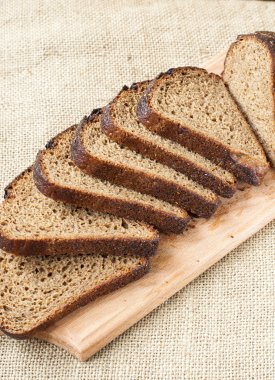 Çuval bezi arka plan üzerinde ahşap kesme tahtası üzerinde taze ekmek dilimi