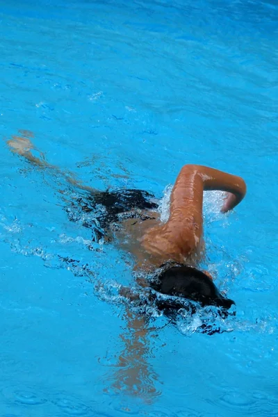Щасливий хлопчик плаває в басейні - стиль передньої повзання з ножицеподібним ударом — стокове фото