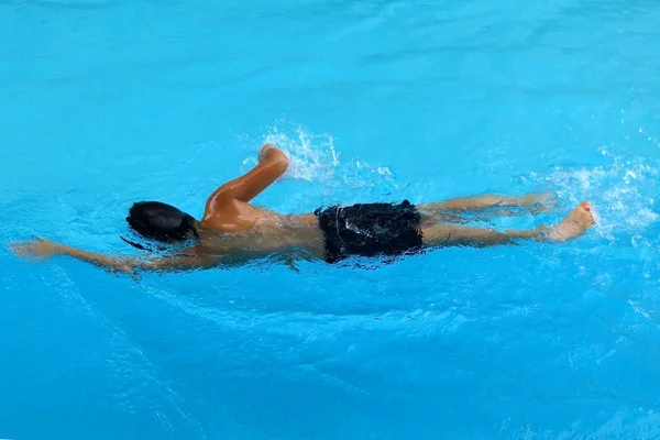 Happy Boy swim in the swimming pool - front crawl style with scissor kick Stok Resim