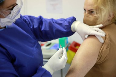 BUCHAREST, ROMANIA - 27 Aralık 2020: Avrupa Aşı Kampanyası 'nın ilk gününde bir tıp personeli covid aşıyı aldı.